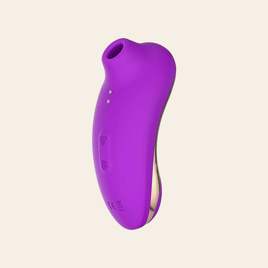 Purple suction vibrator with rose-gold lower body on a soft beige background — Femme Bliss VelvetArc