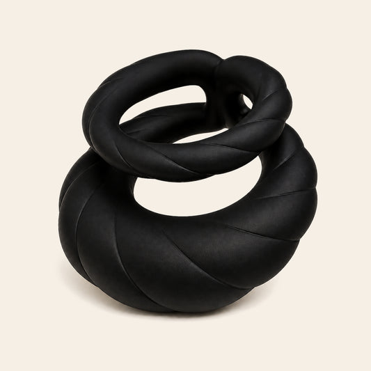 Black silicone dual-motor vibrating cock ring with coiled bands on a soft beige background — Femme Bliss PulseForge Duo