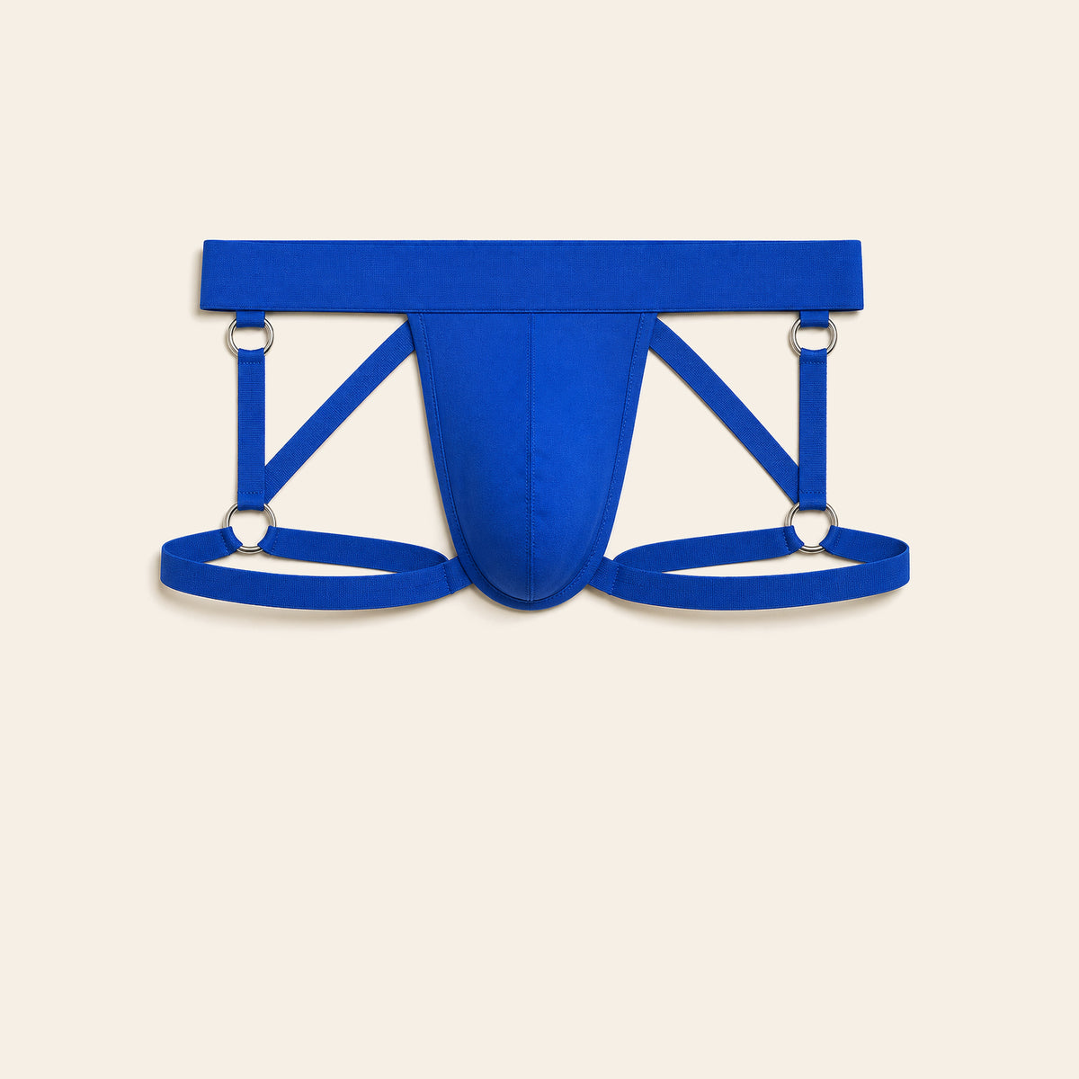 Men's strappy harness brief in royal blue with an open cutout front and elastic thigh straps, on a soft beige background