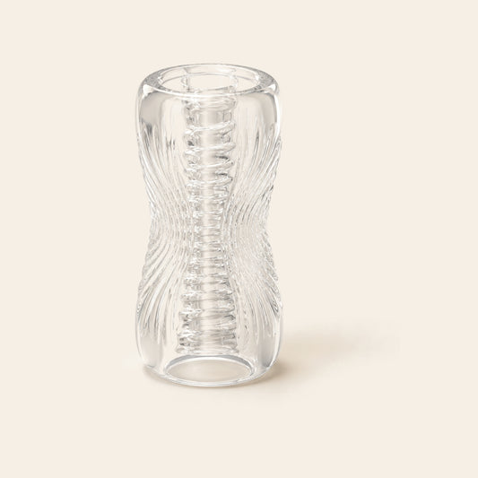 Transparent TPE stroker shown at an angle, the ribbed and nubbed canal visible through the clear wall
