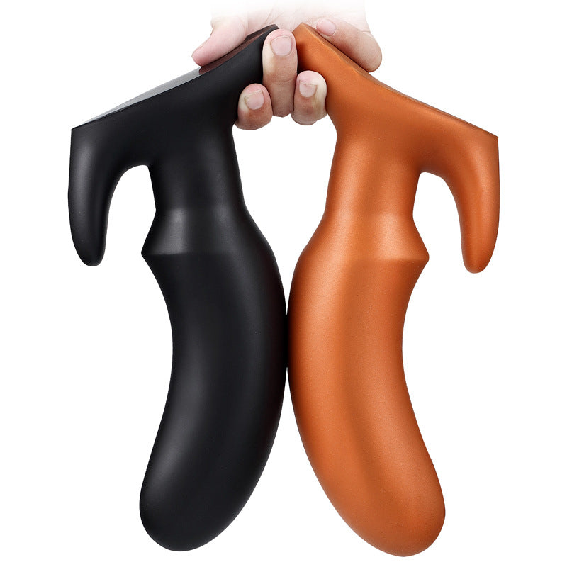 Hand holding a black and a gold tapered silicone butt plug side by side to show flexibility