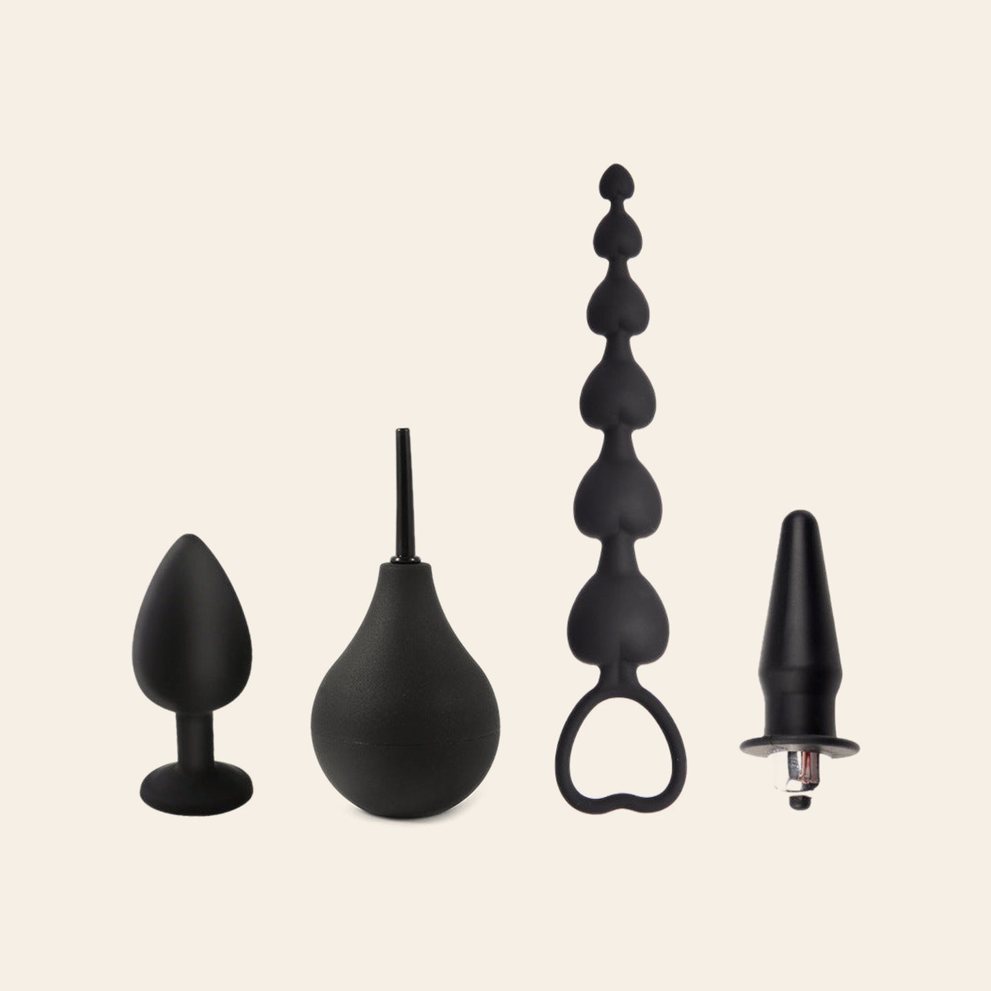 4-in-1 anal care set on a beige background: black silicone butt plug, squeeze-bulb douche, heart-ring anal beads and vibrating plug