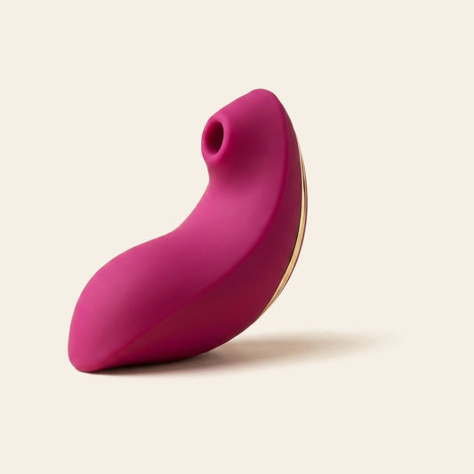 Magenta wearable suction vibrator with gold trim on a soft beige background — Femme Bliss BlissWave