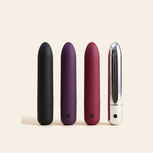 Set of four slim bullet vibrators in black, purple, wine red and chrome on a soft beige background — Femme Bliss Bliss Bullet