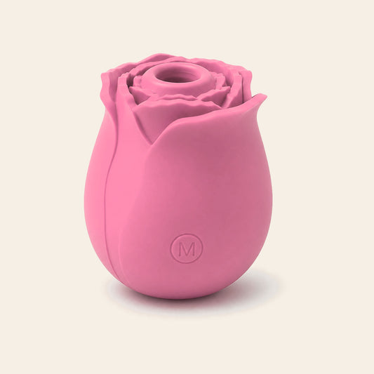 Rose-shaped silicone clitoral suction vibrator in pink on a soft beige background — Femme Bliss BloomPulse Rose