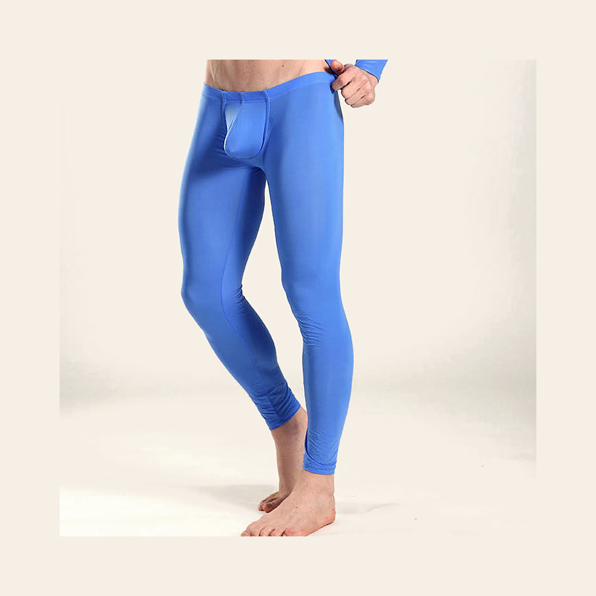 Model wearing men's seamless ice silk leggings in blue with a dual-pouch front, full-length view, on a soft beige background