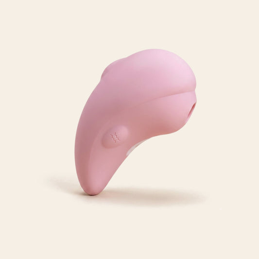 Pink silicone clitoral suction vibrator on a soft beige background — Femme Bliss LunaDove