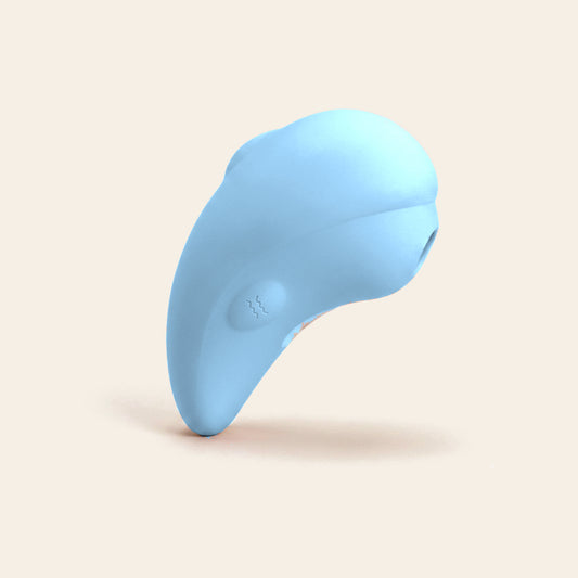 Pale blue dolphin-shaped clitoral suction vibrator on a soft beige background — Femme Bliss LunaDove