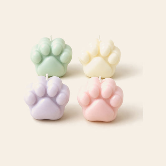 Four paw-shaped low-temperature drip candles in mint, cream, lavender and pink on a soft beige background — Femme Bliss MeltMoment Paw