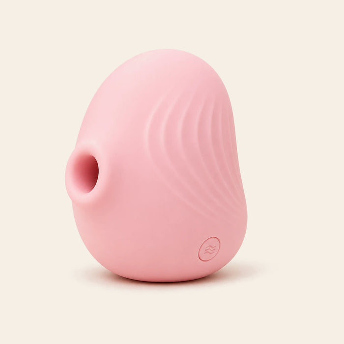 Blush pink petal-shaped silicone suction vibrator with ridged texture on a soft beige background — Femme Bliss PetalPulse