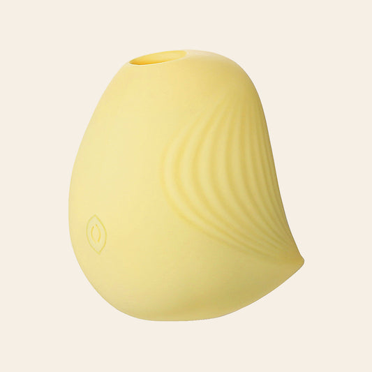 Pale yellow petal-shaped silicone suction vibrator with ridged texture on a soft beige background — Femme Bliss PetalPulse