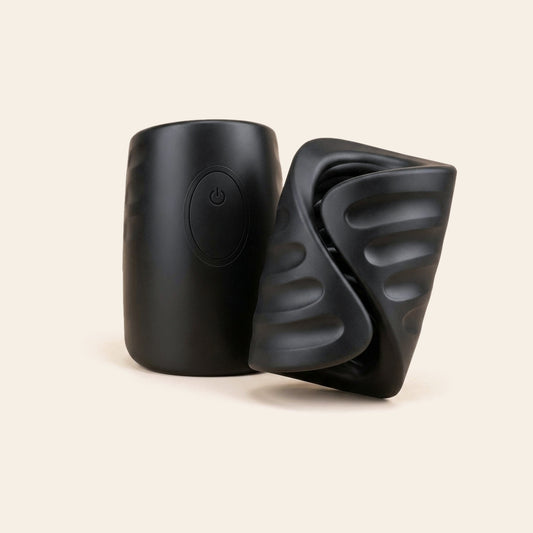 Black vibrating male stroker with ribbed sleeve and hard-shell case on a soft beige background — Femme Bliss PulseGrip