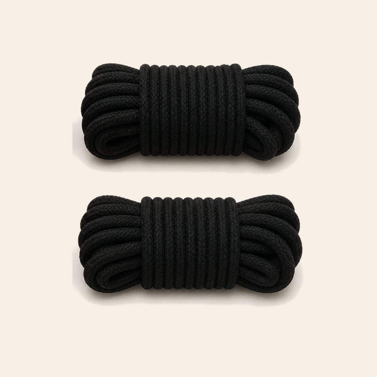 Two coiled black soft bondage ropes on a soft beige background — Femme Bliss SilkBind