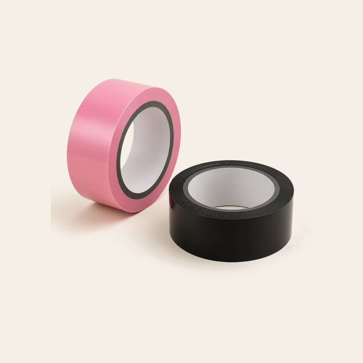 Two rolls of self-cling bondage wrap tape in pink and black on a soft beige background — Femme Bliss StaticWrap