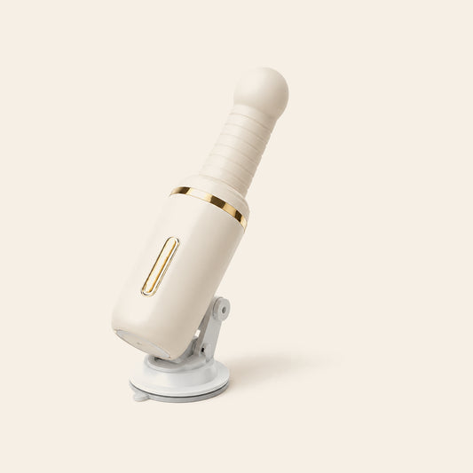 Cream auto-thrusting wand vibrator with ribbed shaft, gold accent ring and suction base on a soft beige background — Femme Bliss SteelBliss Pro