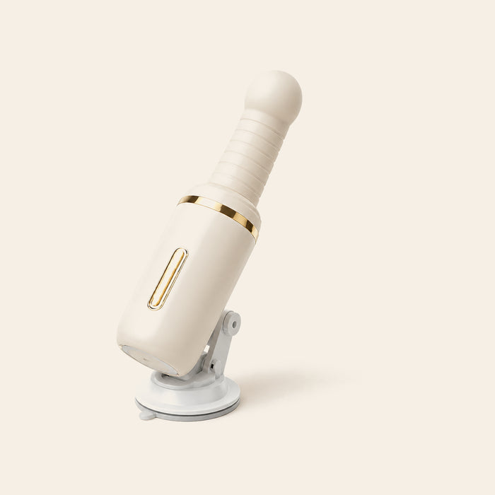 Cream auto-thrusting wand vibrator with ribbed shaft, gold accent ring and suction base on a soft beige background — Femme Bliss SteelBliss Pro