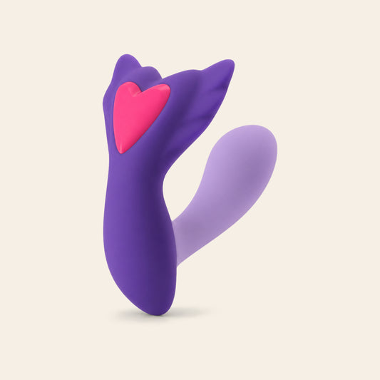 Purple app-controlled wearable vibrator with pink heart inset on a soft beige background — Femme Bliss SweetPulse Sync