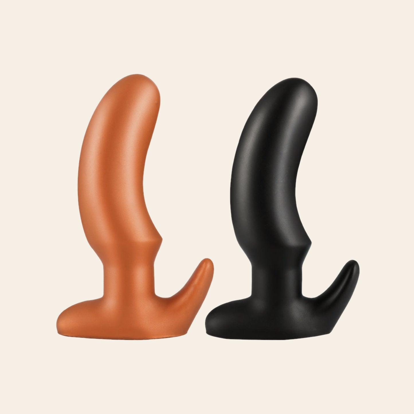 Tapered silicone butt plug with smooth curved shaft and flared T-base, shown in gold and black, on a beige background