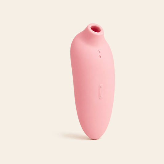 Blush pink suction vibrator with rose-gold lower body on a soft beige background — Femme Bliss VelvetArc